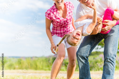 Cuadro en lienzo Family romping on field with parents carrying child