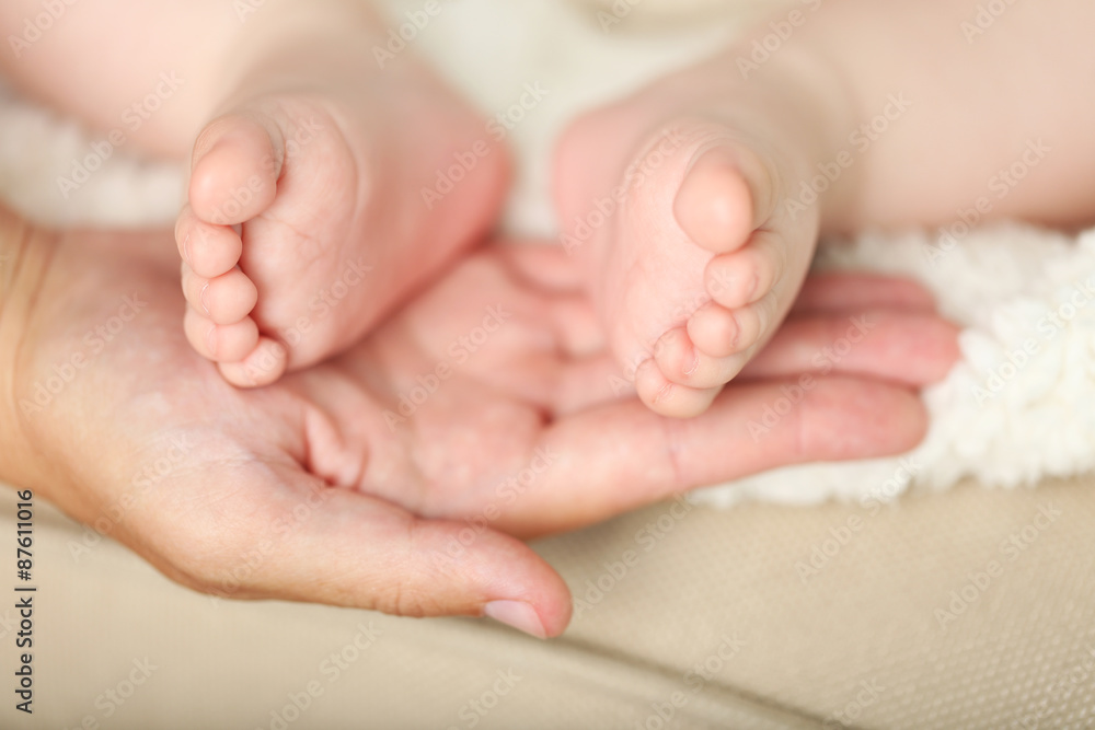 Adult hands holding baby feet, closeup Adult hands holding baby feet, closeup
