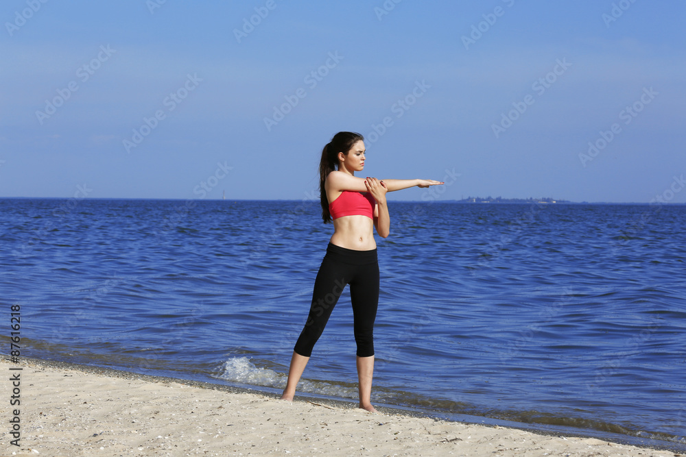 Young sporty woman doing exercise on beach