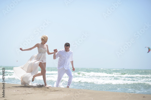 Laughing wedding couple on beach