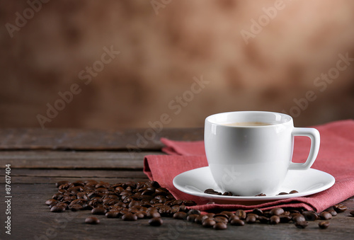 Cup of coffee and beans on blurred background