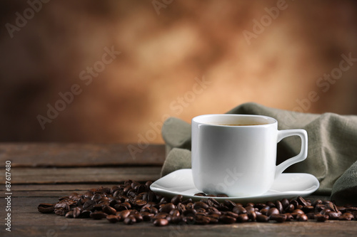 Cup of coffee and beans on blurred background