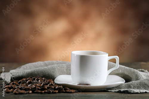 Cup of coffee and beans on blurred background