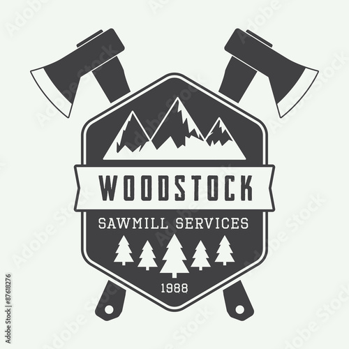 Vintage sawmill logo with axes, rocks, trees