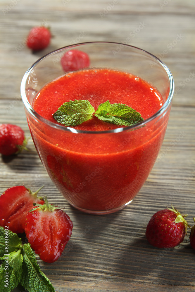 Glass of strawberry smoothie with berries on wooden table close up Glass of strawberry smoothie with berries on wooden table close up