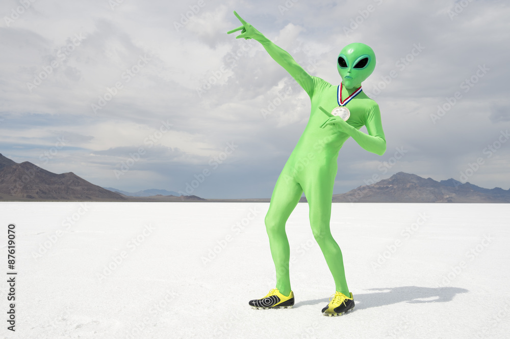 Green alien track star athlete wearing gold medal celebrating with lightning bolt pose on stark white planet background - obrazy, fototapety, plakaty 