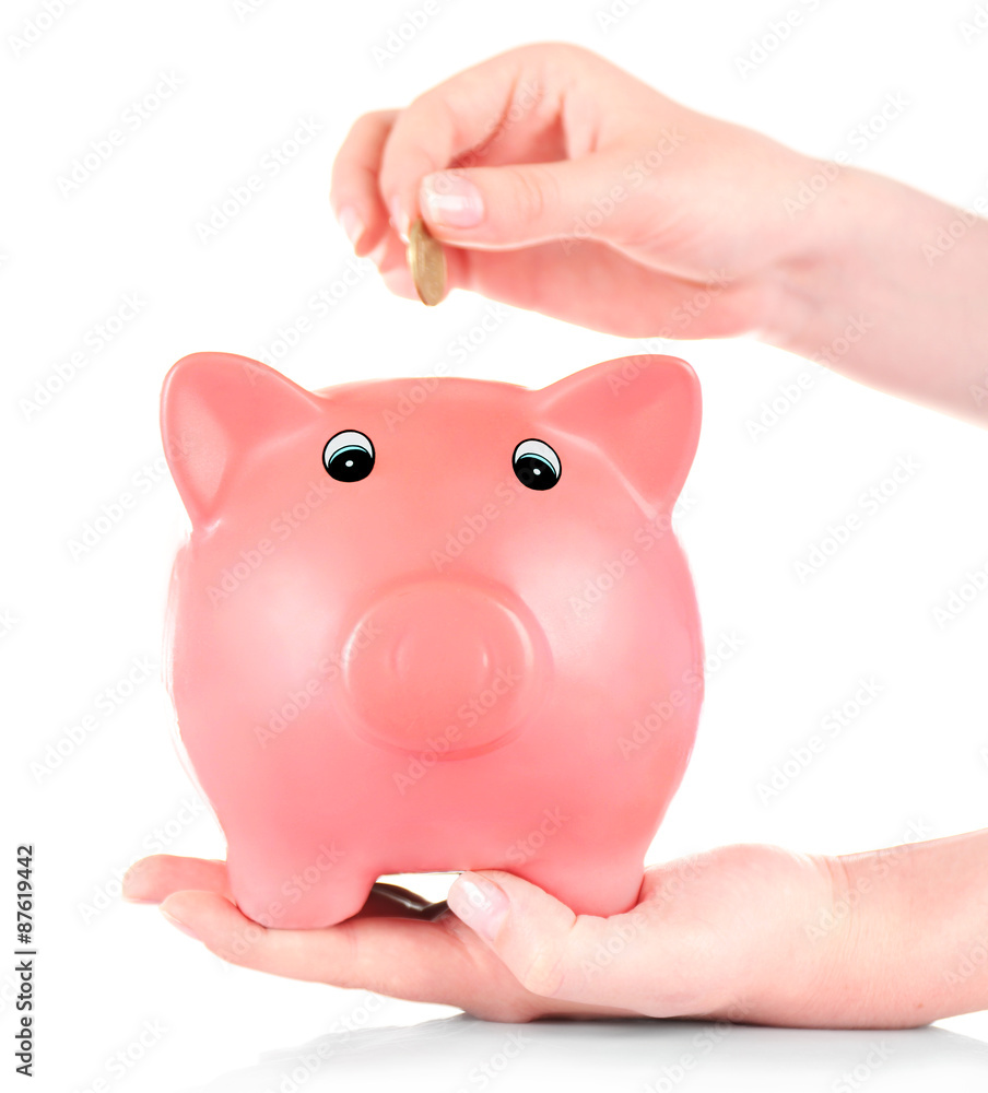 Hand inserting money into piggy bank isolated on white