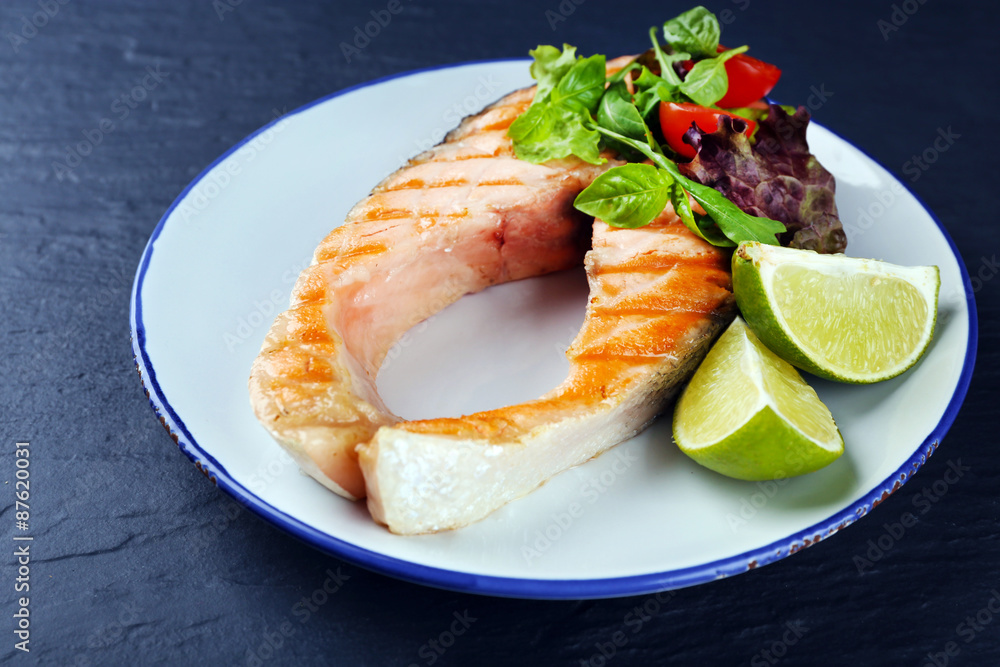 Tasty grilled salmon with lime and salad on table close up Tasty grilled salmon with lime and salad on table close up