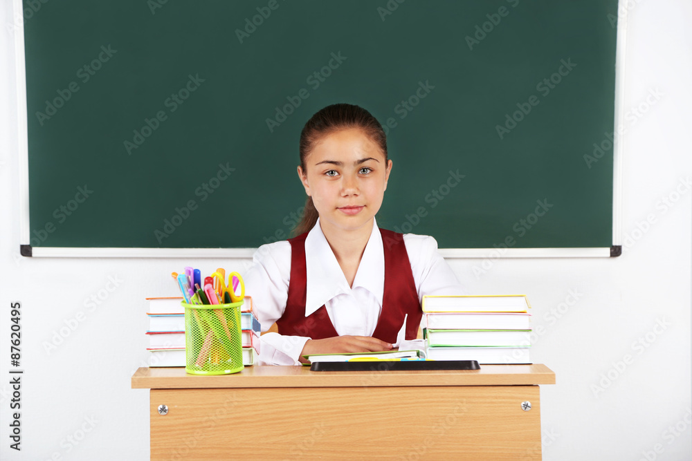 Beautiful little schoolgirl in classroom near blackboard Beautiful little schoolgirl in classroom near blackboard