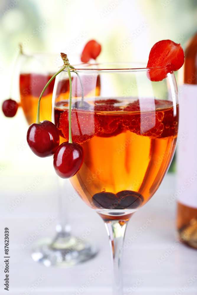 Glasses of wine with berries on light blurred background Glasses of wine with berries on light blurred background