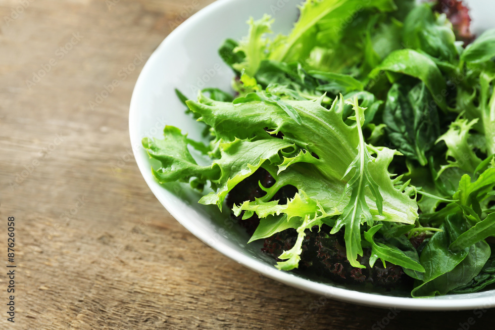 Bowl of mixed green salad on wooden table, closeup Bowl of mixed green salad on wooden table, closeup