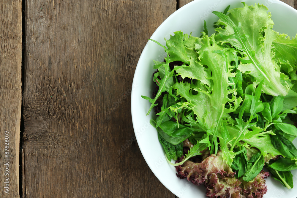 Bowl of mixed green salad on wooden background Bowl of mixed green salad on wooden background