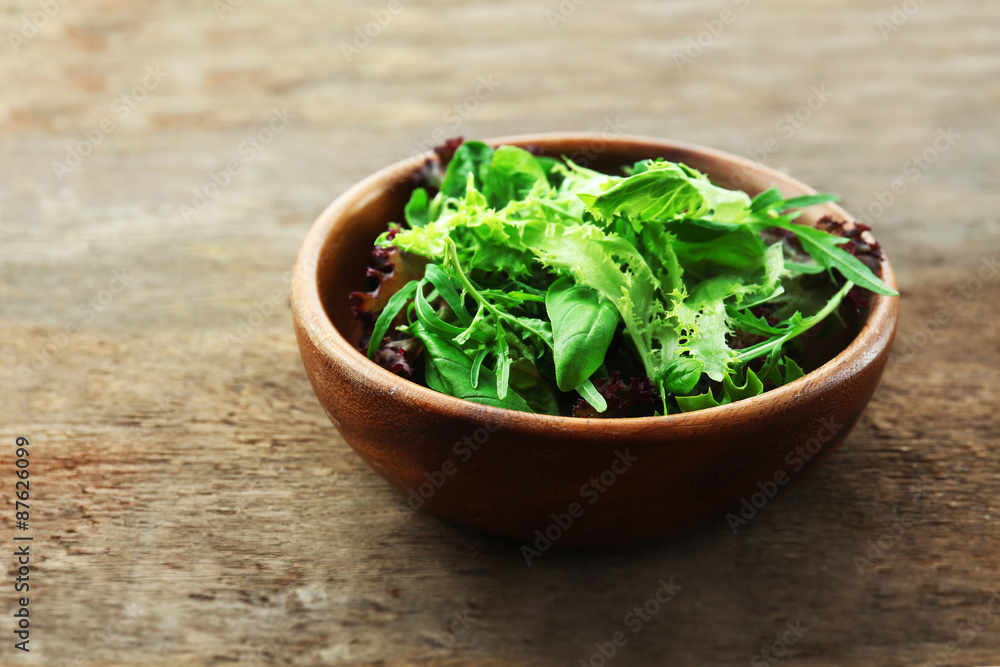 Bowl of mixed green salad on wooden background Bowl of mixed green salad on wooden background