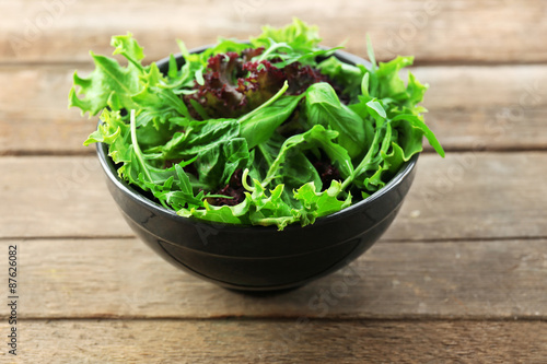 Bowl of mixed green salad on wooden background