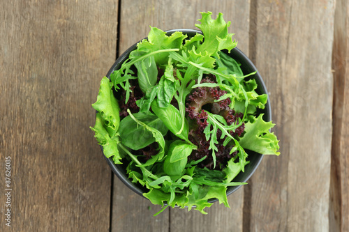 Bowl of mixed green salad on wooden background