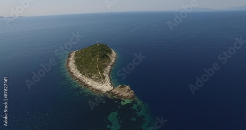 Escena aérea con dron de pequeña isla con un faro aislada en mar. Cámara se acerca a la isla, cambia ángulo de visión. Costa dálmata, el mar Adriático. Coratia. photo