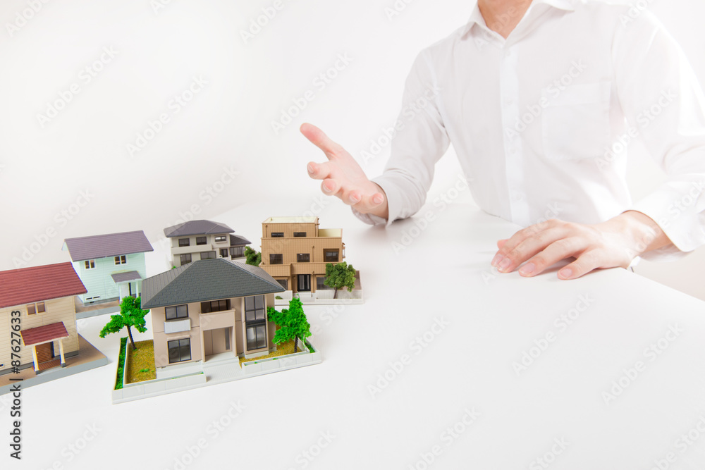 白いテーブルで一戸建てをプレゼンしている男性 白いテーブルで一戸建てをプレゼンしている男性