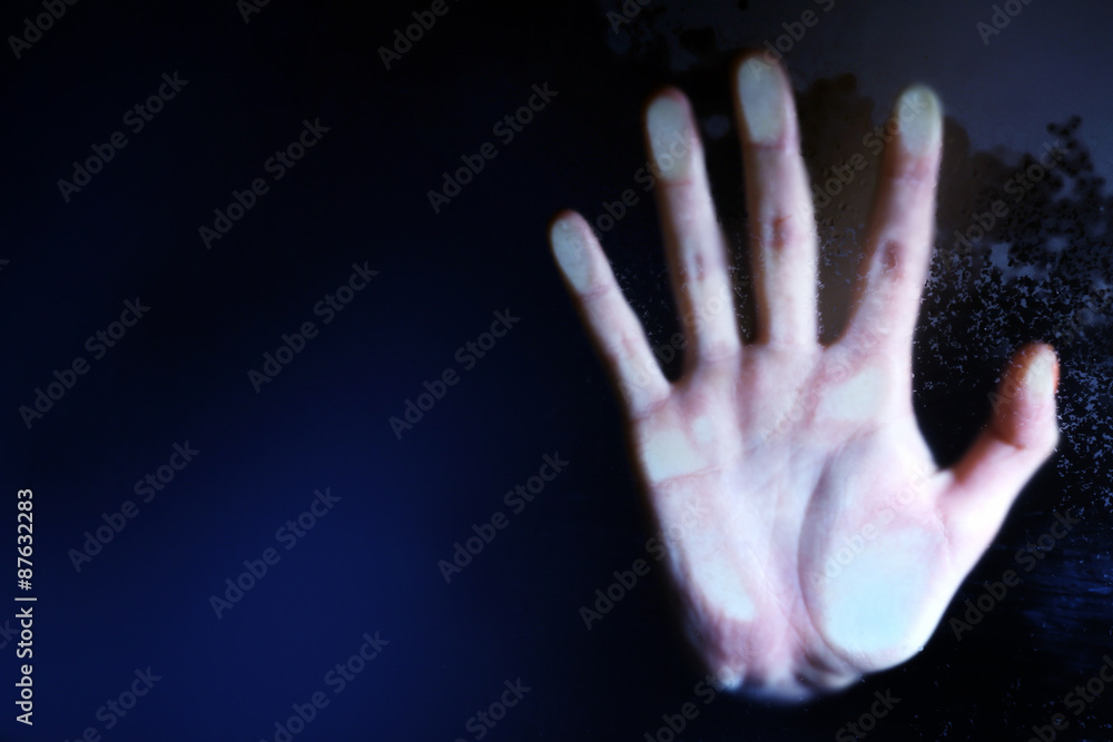 Female hand behind wet glass, close-up Female hand behind wet glass, close-up