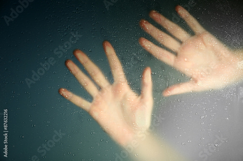 Female hand behind wet glass, close-up