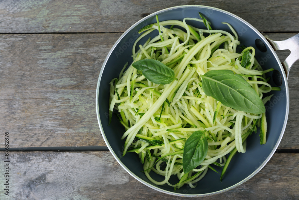 Grated zucchini and squash in pan on wooden table close up Grated zucchini and squash in pan on wooden table close up