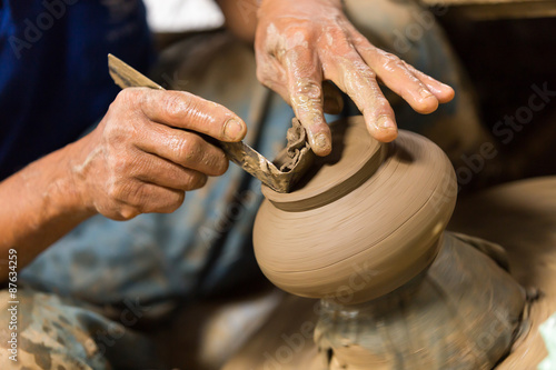 Hands working with clay on pottery wheel