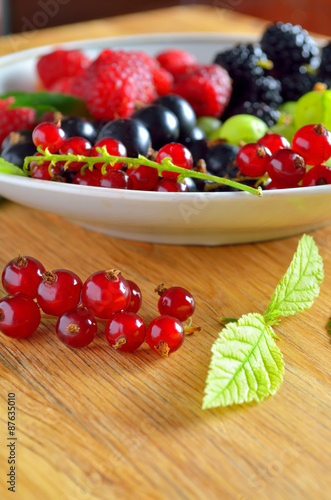 Assorted fresh garden berries on a  wooden background  close-up  raspberry   black and red currant  gooseberry  blackberry.