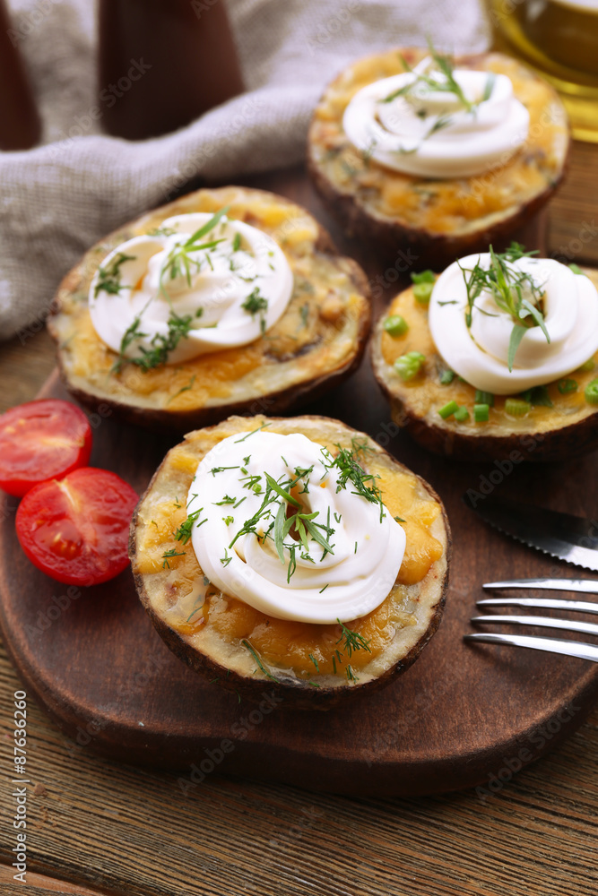 Baked potato with mayonnaise and herbs on wooden cutting board, closeup Baked potato with mayonnaise and herbs on wooden cutting board, closeup