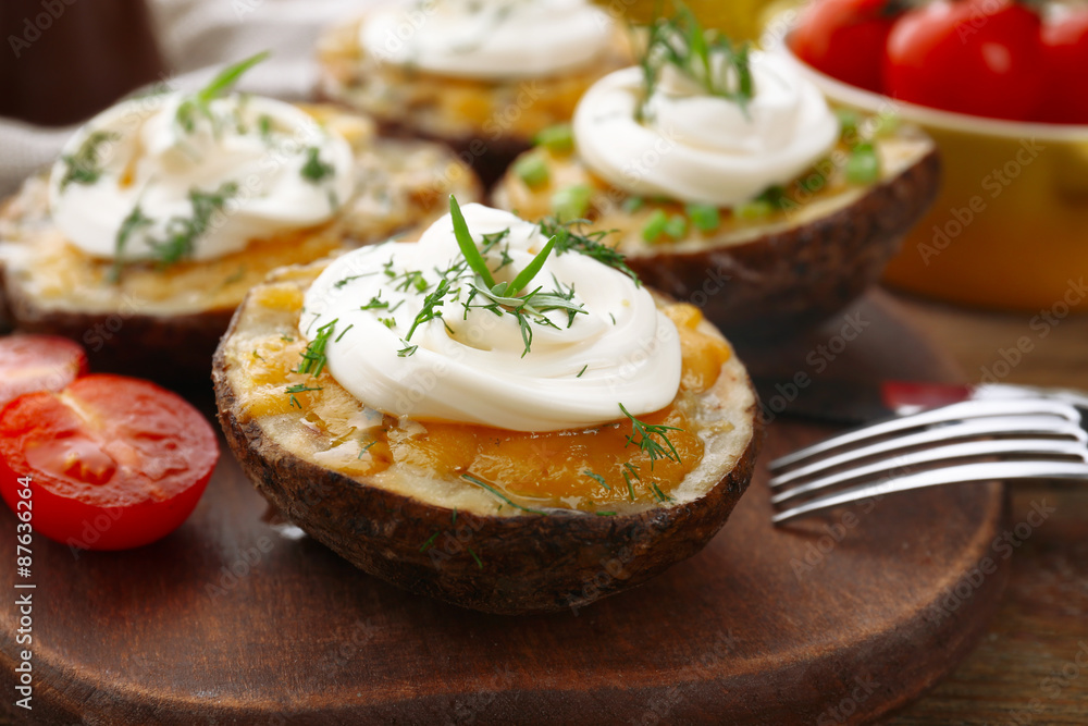 Baked potato with mayonnaise and herbs on wooden cutting board, closeup Baked potato with mayonnaise and herbs on wooden cutting board, closeup