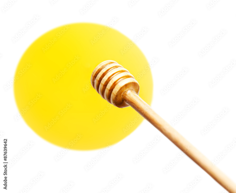 Wooden honey dipper with yellow honey flowing drops isolated on Wooden honey dipper with yellow honey flowing drops isolated on