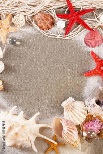 Collection of seashells with sand on sackcloth background