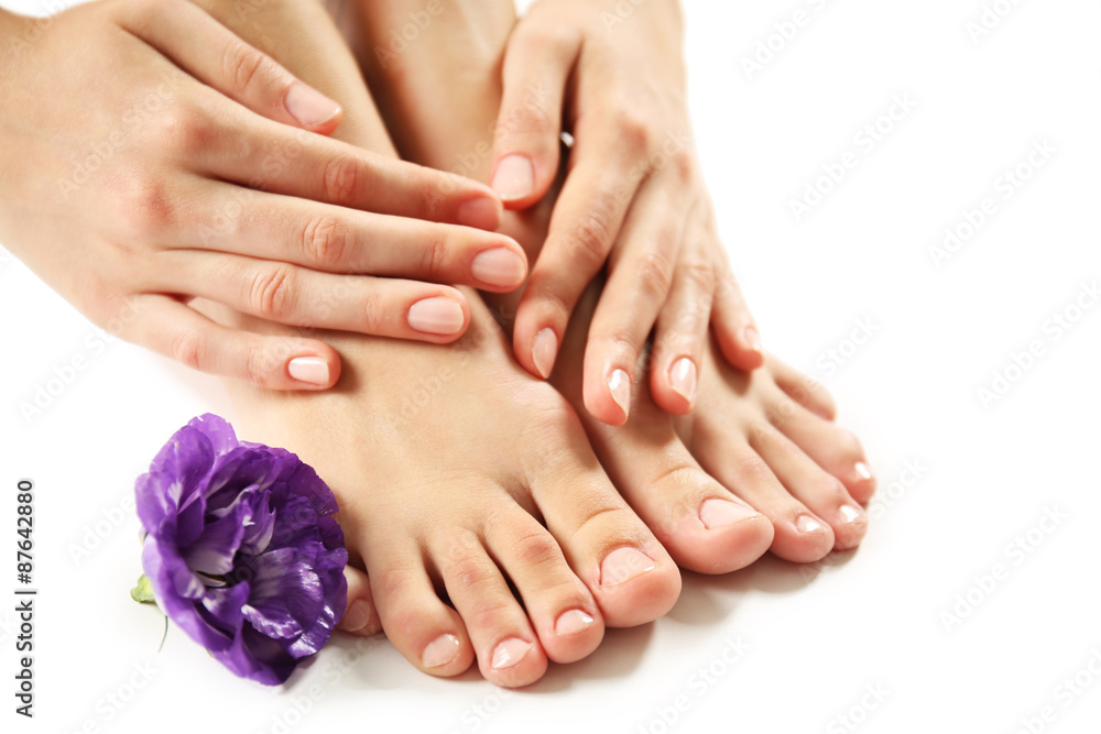 Fototapeta premium Female feet at spa pedicure procedure with flower isolated on white