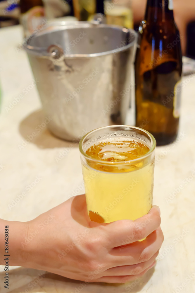 Hand holding a glass of beer on a table Hand holding a glass of beer on a table