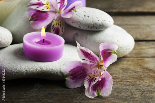 Spa still life with purple flowers, pebbles and candlelight on wooden table, closeup