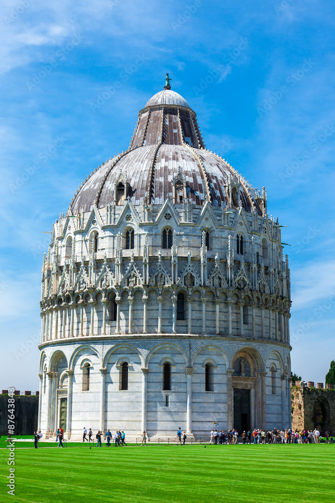 PISA, ITALY - MAY 10, 2014: Tourists on Square of Miracles visiting Baptistery, dedicated to St. John the Baptist.The round Romanesque building was begun in the mid 12th century.