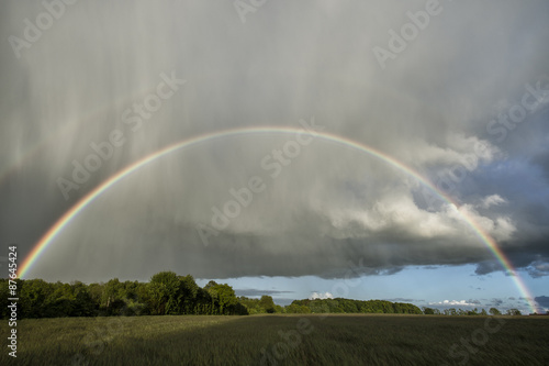 Double rainbow over a field with sunshine and rain