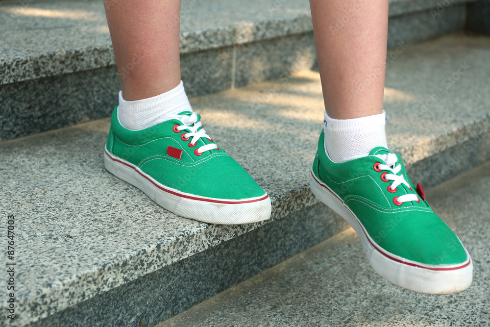 Female feet in green gumshoes on stone stairs