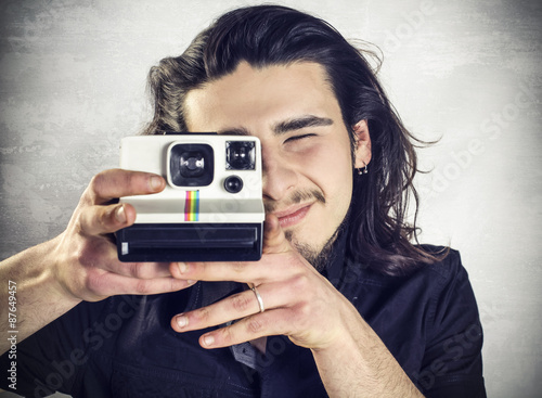 Young man taking a picture with vintage camera photo