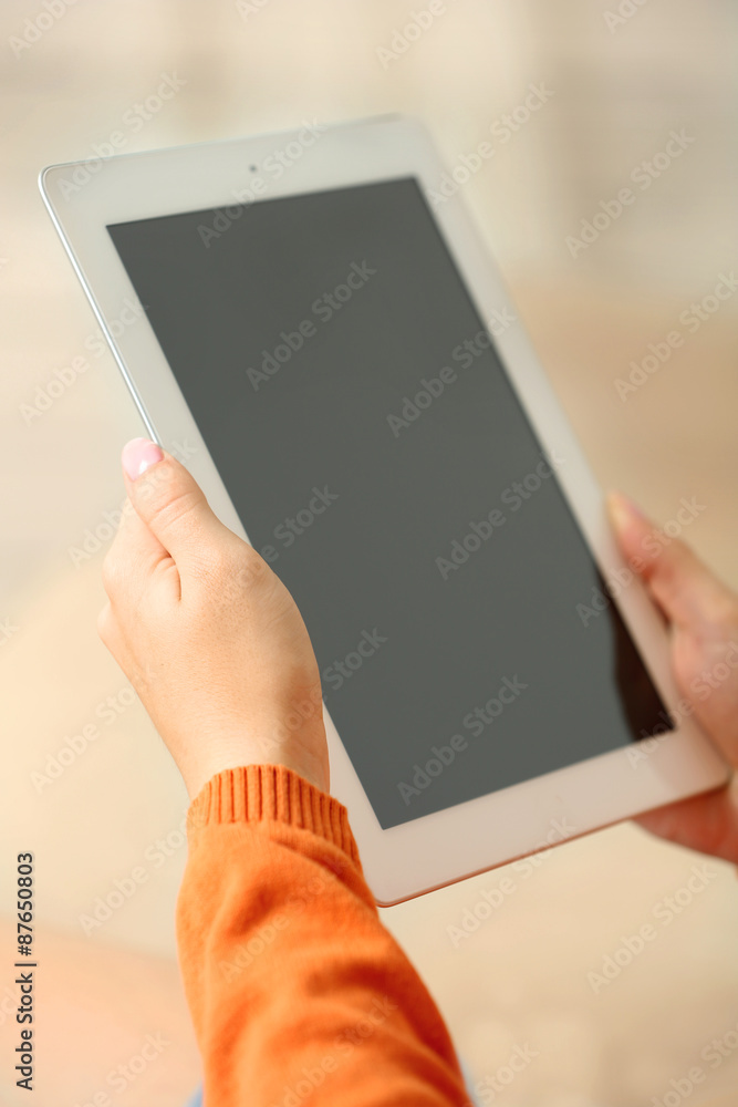 Female hand holding PC tablet on home interior background Female hand holding PC tablet on home interior background