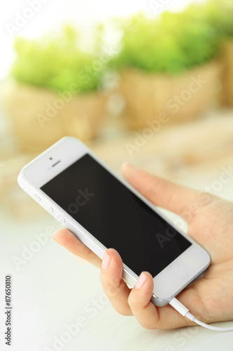 Music smartphone in female hand, on light background