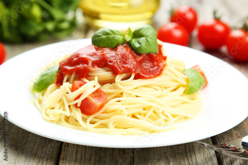 Spaghetti with tomatoes and basil on plate on grey wooden backgr