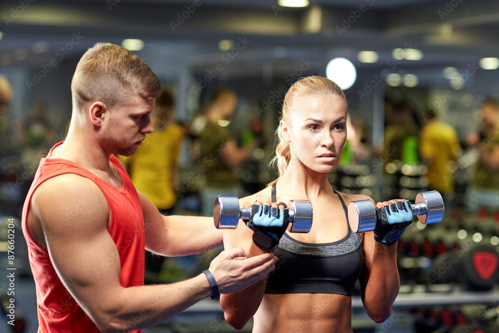young couple with dumbbells flexing muscles in gym