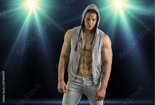 Confident  attractive young man with open vest on muscular torso