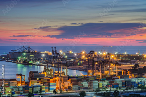 Container Cargo freight ship with working crane bridge in shipyard at dusk for Logistic Import Export background