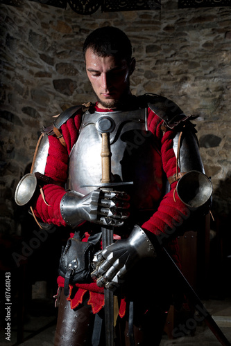 Knight Standing With Head Bowed in Prayer and Metal Sword 