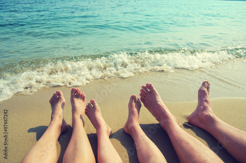 Female, children's and male feet on a beach against the sea in a summer sunny day. Family holiday
