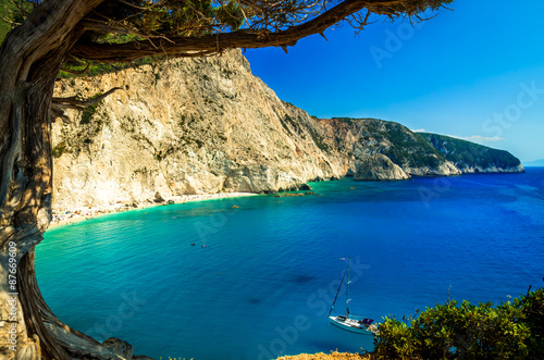 Porto Katsiki beach in Lefkada island, Greece. Beautiful view over the beach. The water is turquoise and there are tourists on the beach and a boat on the sea.