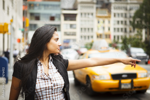 A woman hailing a taxi on a city street.