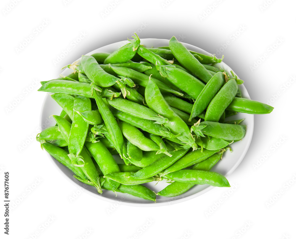 Small pile of green peas in pods on white plate Small pile of green peas in pods on white plate