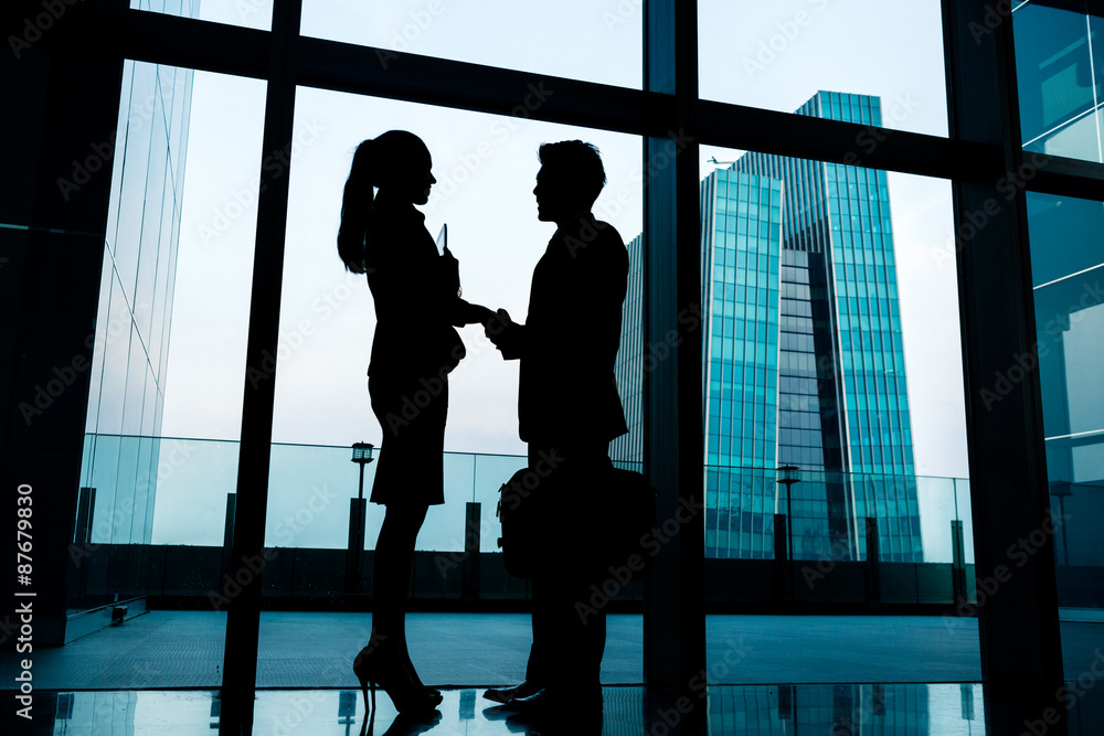 Silhouettes of backlit business people handshake Silhouettes of backlit business people handshake