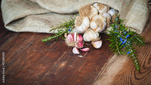 Garlic and rosemary in rustic sack on the wooden table